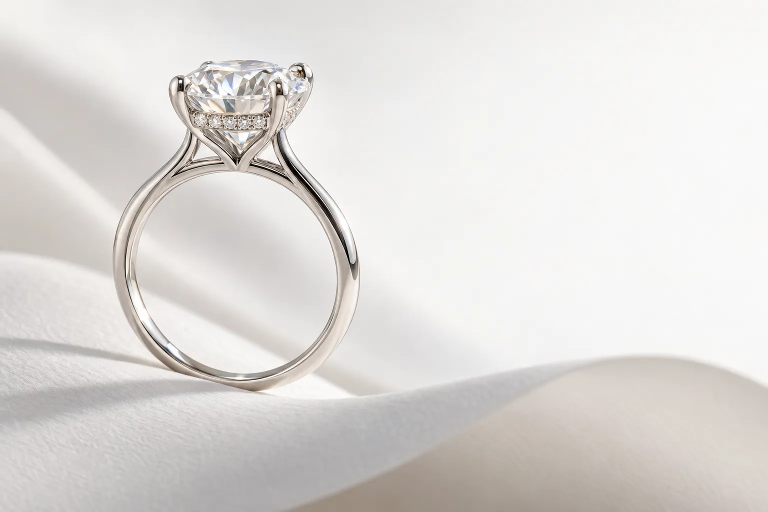 Side view of an engagement ring with a 2 carat diamond: strong prongs and a hidden halo of small diamonds below the stone