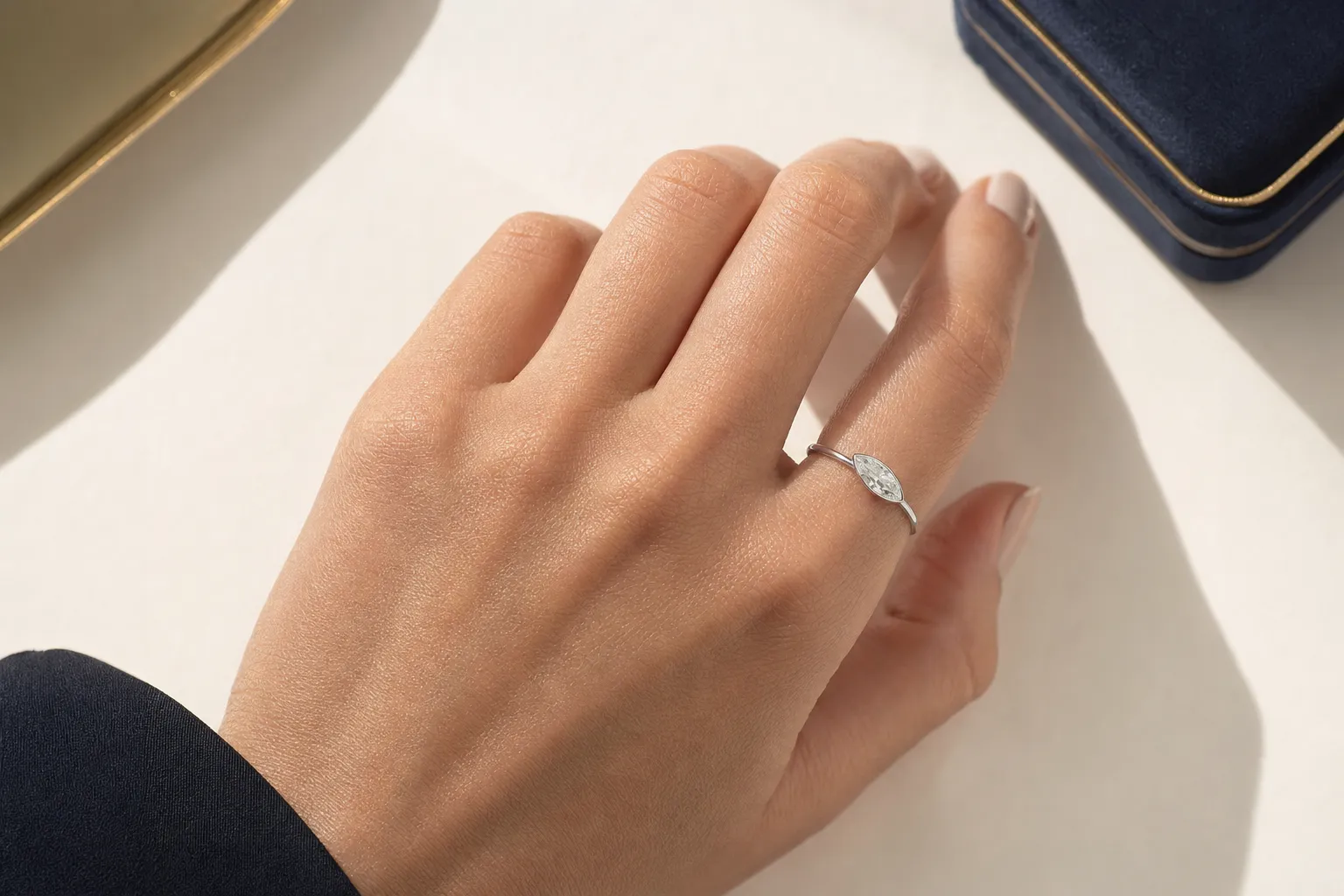 Ein Verlobungsring mit Marquise-Diamant in Weissgold quer über den Finger getragen, modernes Erscheinungsbild