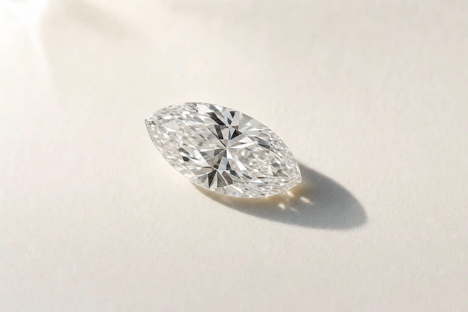 Ein loser Marquise-Diamant mit zwei spitzen Enden liegt auf warmweissem Papier, Makroaufnahme
