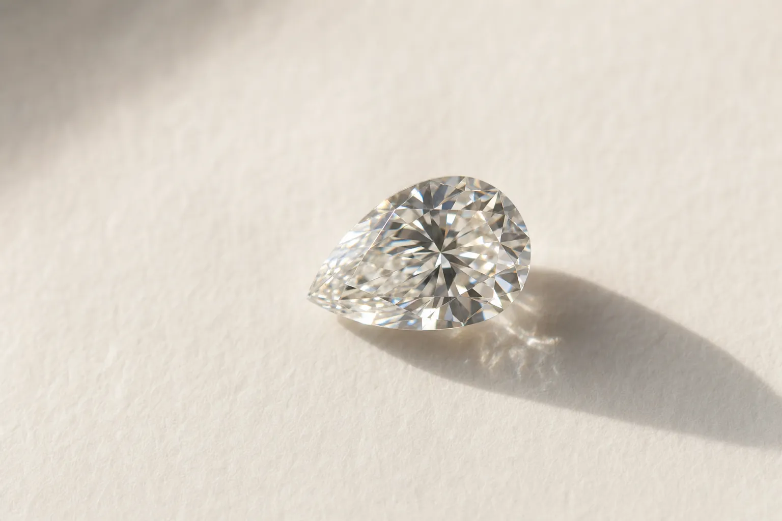 Loser Tropfen-Diamant auf warmem weissem Papier, typischer Seitenstein für einen Trilogie-Ring