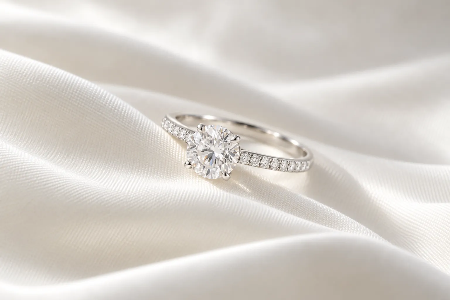 Verlobungsring mit Diamant: Platin-Solitär mit rundem Brillanten und feinem Pavé auf der Schiene, auf weisser Seide