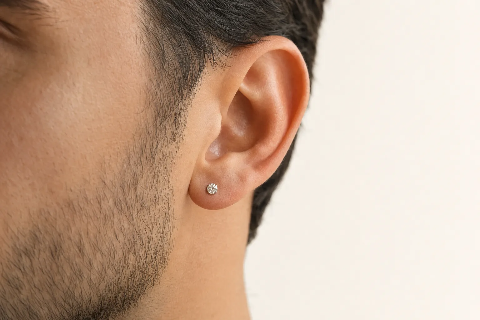 Ein einzelner Diamant-Ohrstecker am Ohr eines Mannes, Nahaufnahme bei Tageslicht