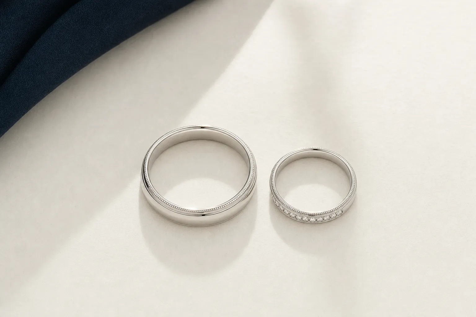 Ein Paar Eheringe aus hellem Weissgold, ein breiterer und ein schmalerer Ring, nebeneinander
