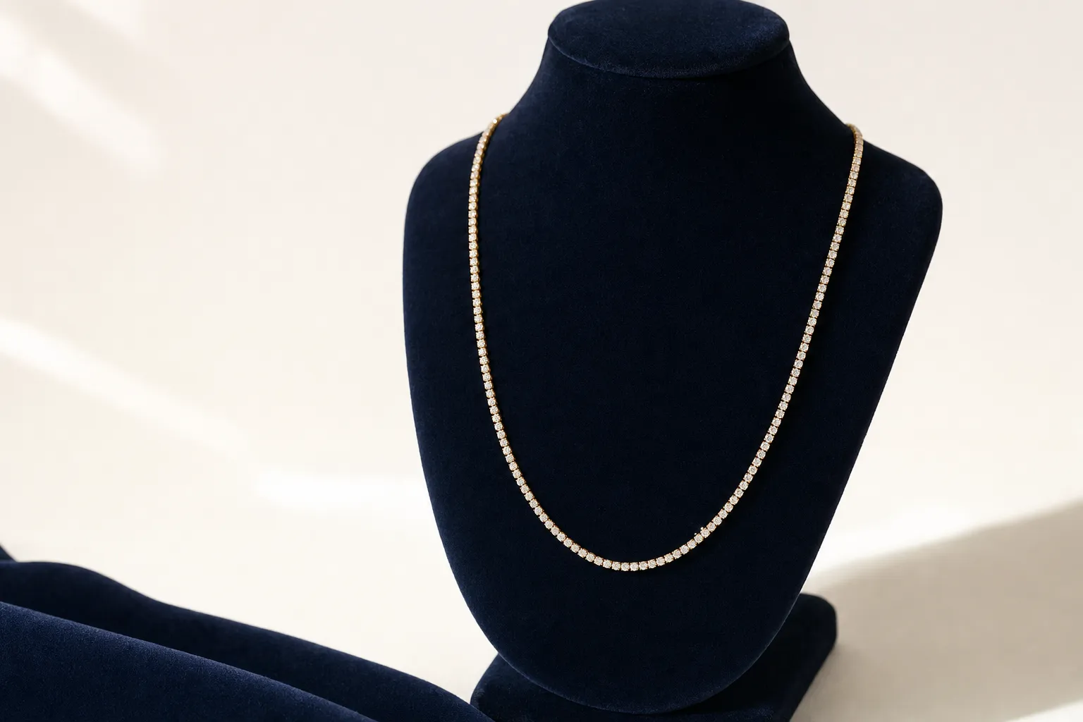 Diamant-Tennis-Chain hängend an einer Navy-Büste vor warmem Weiss