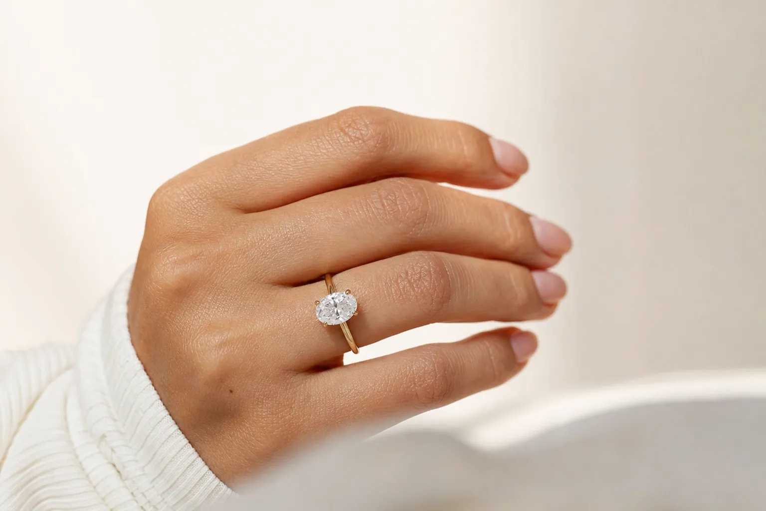 Ein grosser ovaler Labordiamant-Solitärring in Gelbgold an einer Hand im Tageslicht