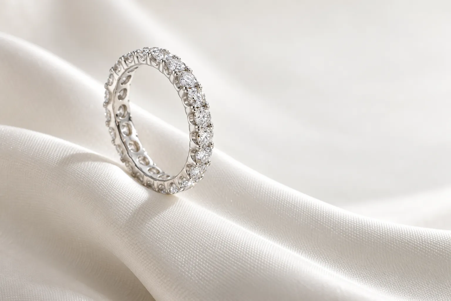 Eternity ring in white gold set all the way round with small brilliant diamonds, on a wave of ivory silk
