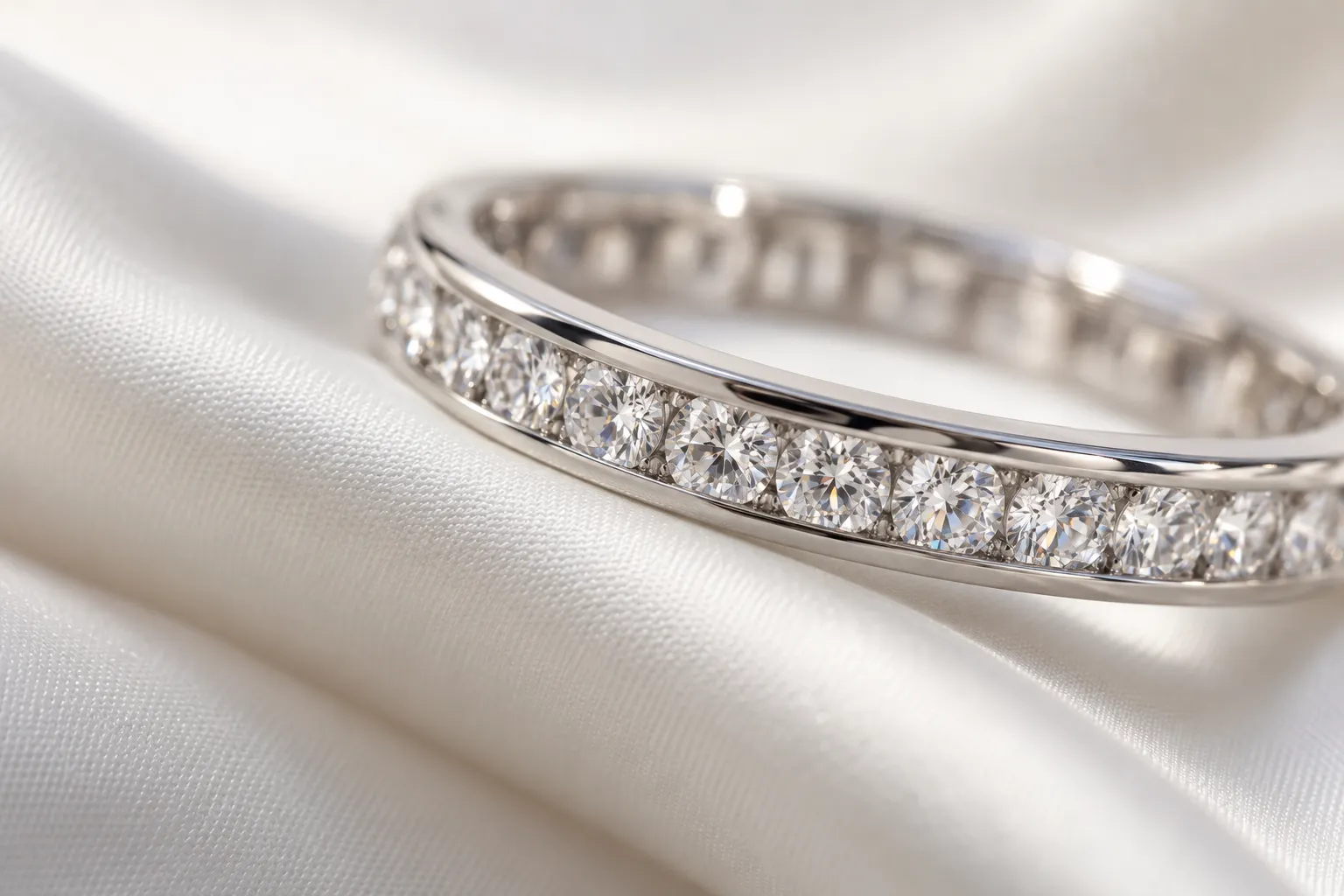 Detail of a platinum eternity ring: small brilliant diamonds side by side in a channel setting between two metal rails