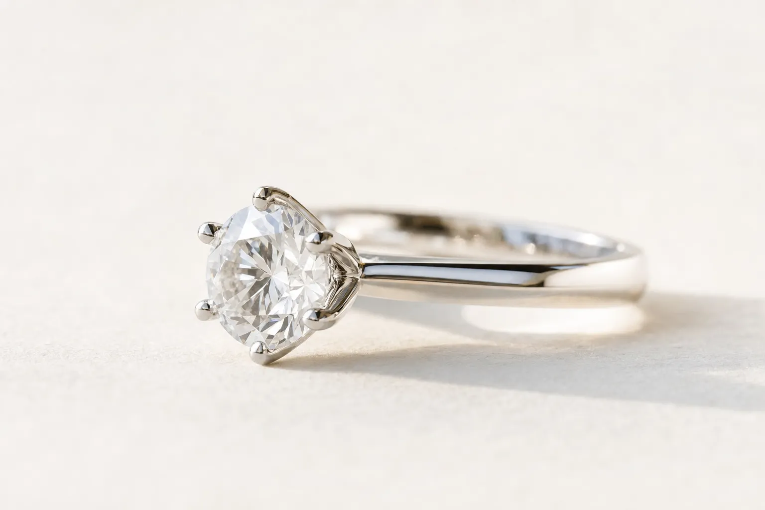 Six-prong setting holding a round diamond in white gold, close-up side view